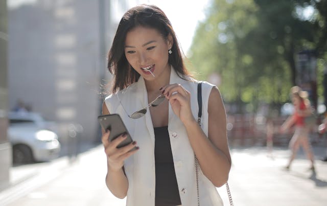 Une personne marchant dans la rue et regardant son téléphone.