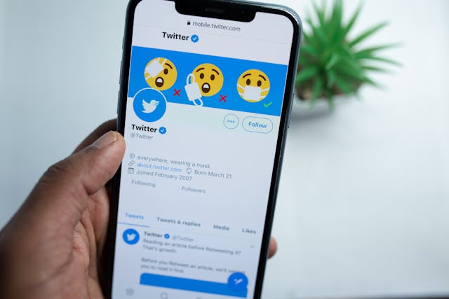 Een persoon met een telefoon die de officiële pagina van Twitter weergeeft op de website van Twitter.