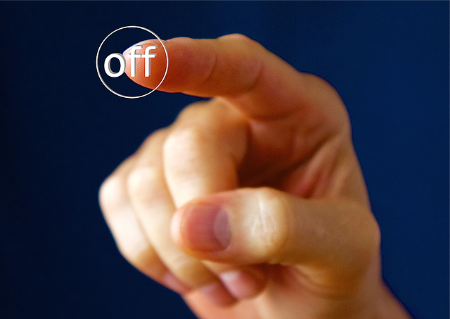 A person’s finger presses an off button.