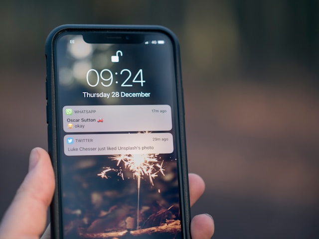 A person holding an iPhone with a Twitter notification on the screen.