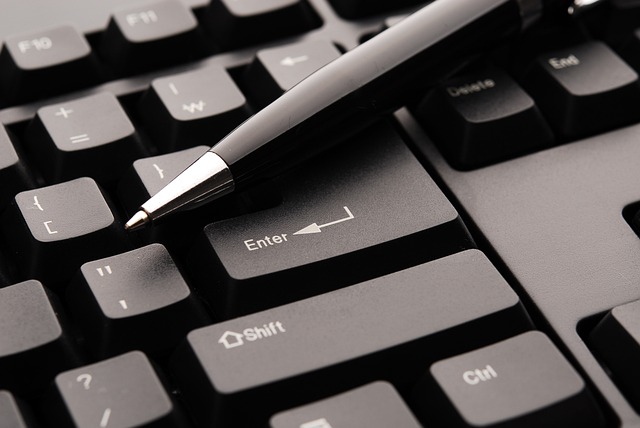 A black biro lies atop a keyboard.
